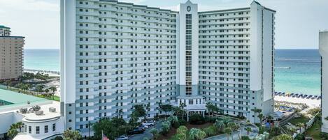 A high-rise hotel with a central tower, multiple floors, and a beach view.