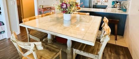 A dining area with a marble table, wooden chairs, a vase of flowers, and a hanging light fixture.