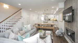 Un salon moderne avec un escalier, un coin repas et une cuisine.
