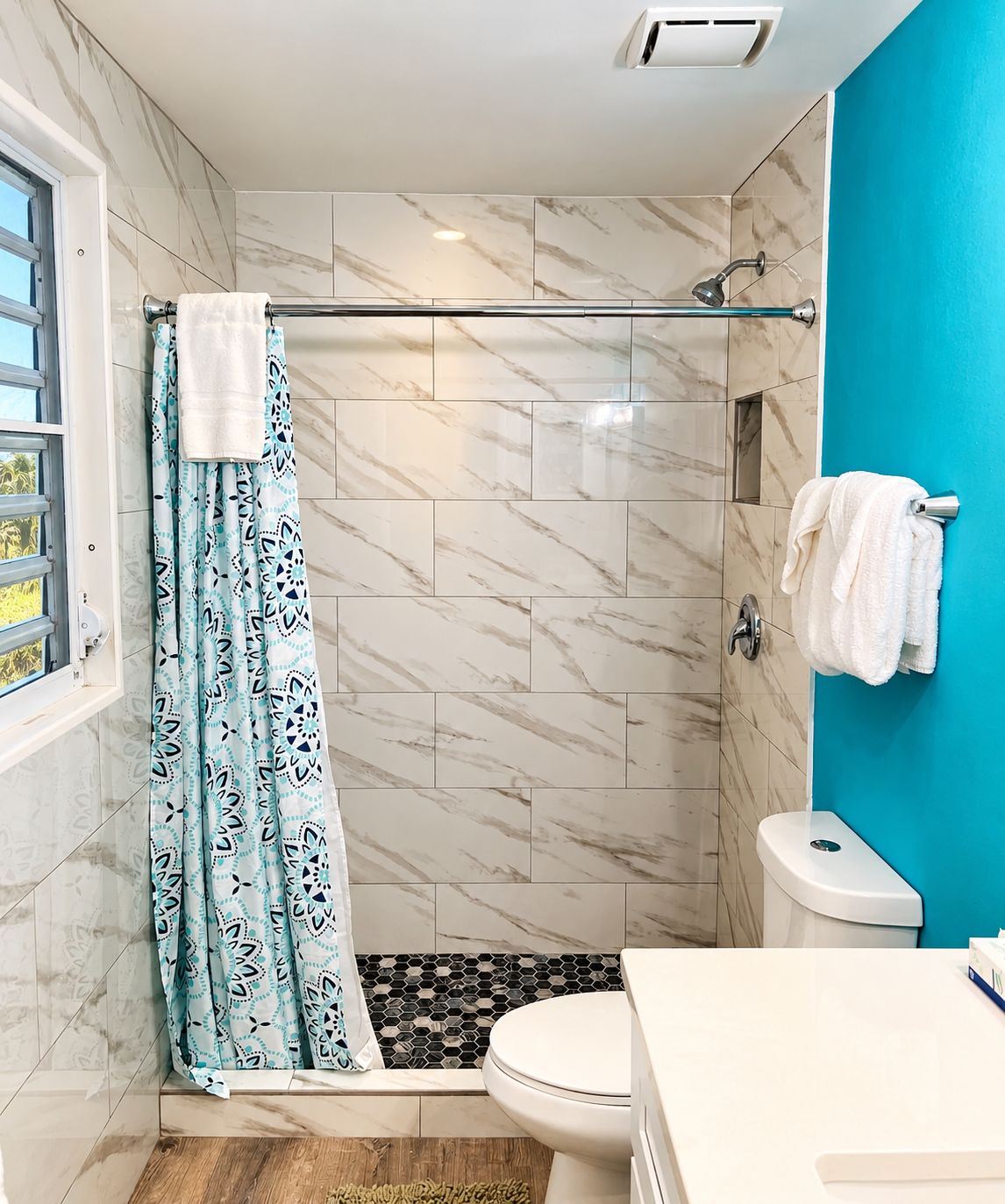 Une salle de bain avec une douche, des toilettes et une fenêtre.