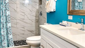Une salle de bain équipée d’une douche, de toilettes, d’un lavabo et d’un miroir avec éclairage.