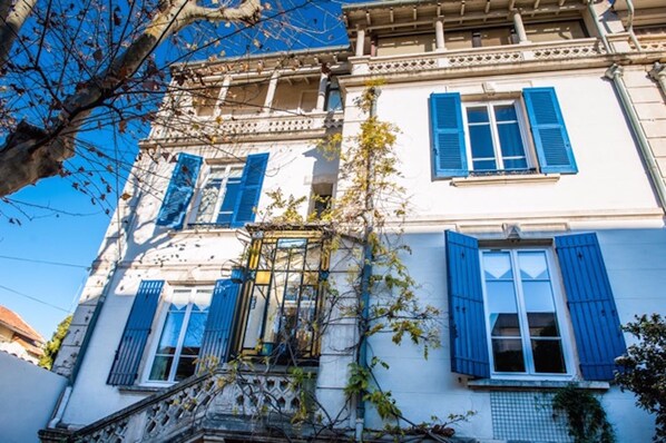 Ein mehrstöckiges Gebäude mit weißen Wänden und blauen Fensterläden.