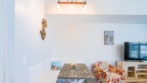 Un comedor con una mesa de madera y banco, un televisor y adornos en la pared.