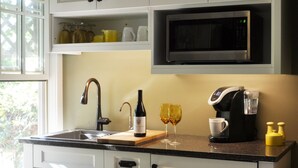 A modern kitchen with white cabinetry, a stainless steel sink, a microwave, and a coffee maker.