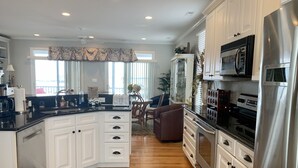 A modern kitchen with white cabinetry, stainless steel appliances, and a wooden floor. - Beautiful Retreat with Ocean & Sound Views (Atlantic Beach)