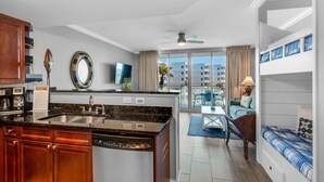 A modern kitchen with a built-in dishwasher, a dining area with a table and chairs, and a balcony with a view of the city.