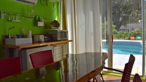 A kitchen with a glass table, red chairs, and a view of a swimming pool.
