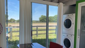 A room with a large window, a table, chairs, and a washing machine.