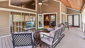 A covered outdoor area with a ceiling fan, a sofa set, a TV, and a small table with a plant.