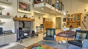 Amplia sala de estar con chimenea, muebles modernos y comedor con candelabro.