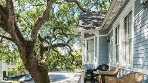 Une véranda avec des meubles en osier et un grand arbre.
