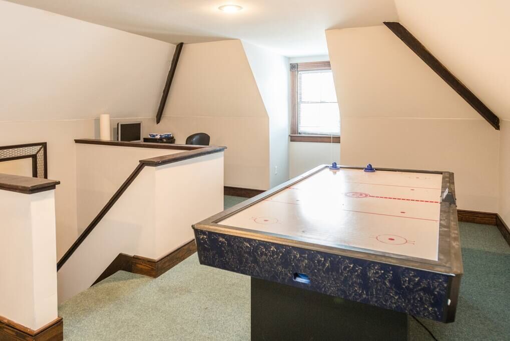 A room with a pool table, a small desk, and a window.
