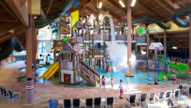 Un parco acquatico al chiuso con scivoli, giochi d'acqua e aree gioco.