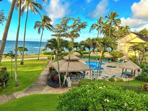 A resort with a pool area, lounge chairs, and a view of the ocean. - Top Floor Beautiful Ocean View Studio (Kapaa)