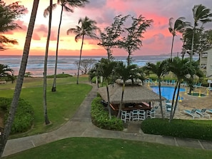 Ein Resort mit Poolbereich, Liegestühlen und Blick auf das Meer bei Sonnenuntergang.
