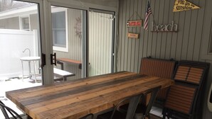 Una mesa de madera con sillas de metal, un banco y una mesita afuera.