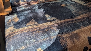 A bed with patterned bedding, a window with a view, and wooden cabinetry. - Sandpiper 40ft RV @EvansCliff /HotTub on Covered Deck! new 2026 location (Hot Springs)
