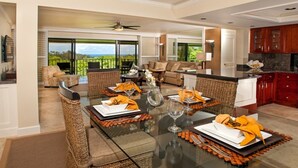 Un comedor amplio con una mesa de vidrio, sillas de mimbre y vistas al exterior.