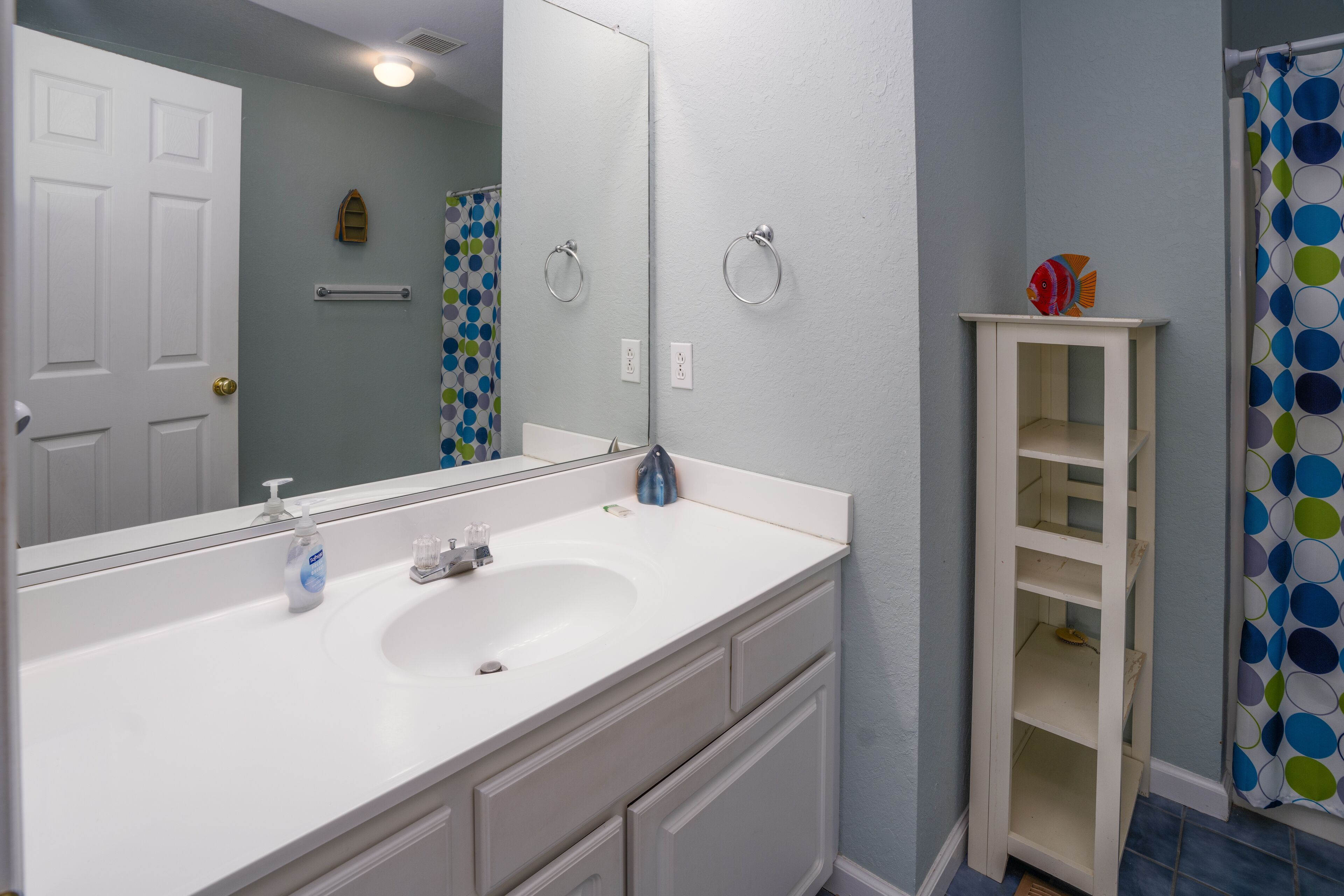 Une salle de bain avec un lavabo blanc, un miroir et un meuble blanc.