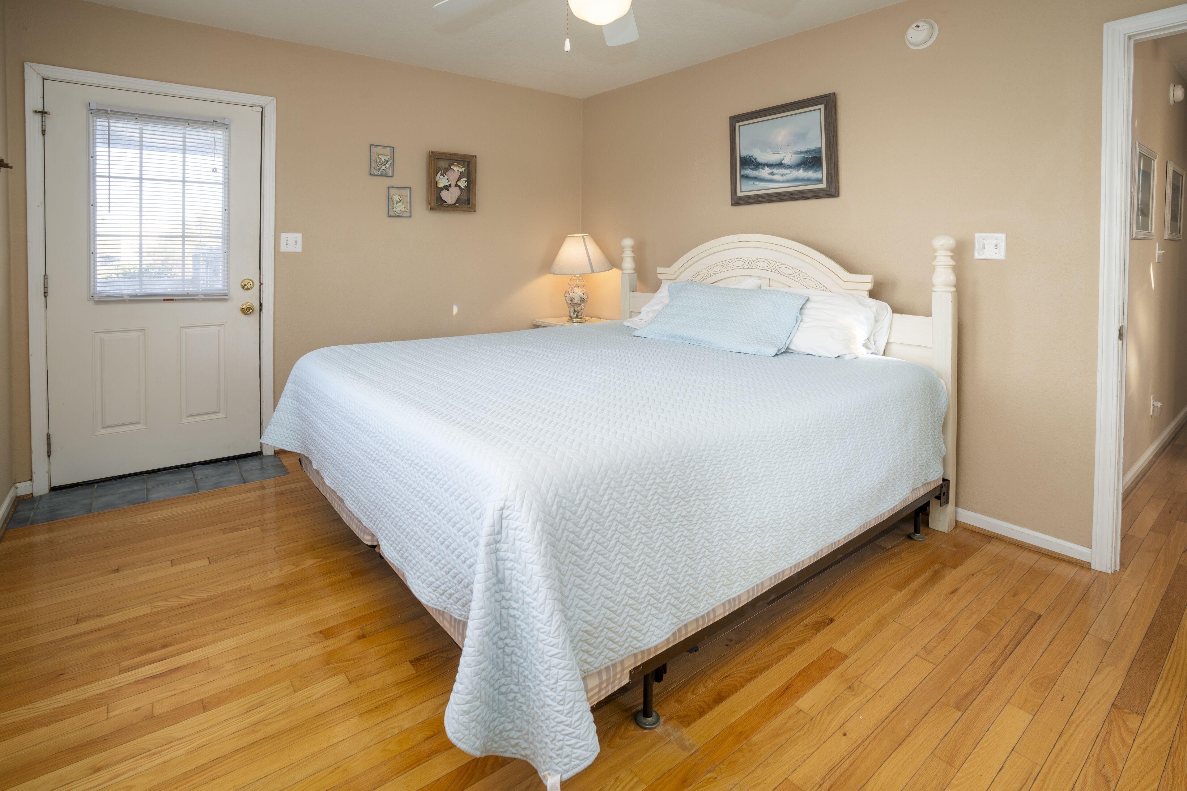 Une chambre à coucher avec un lit, un plancher en bois, une porte et une fenêtre.
