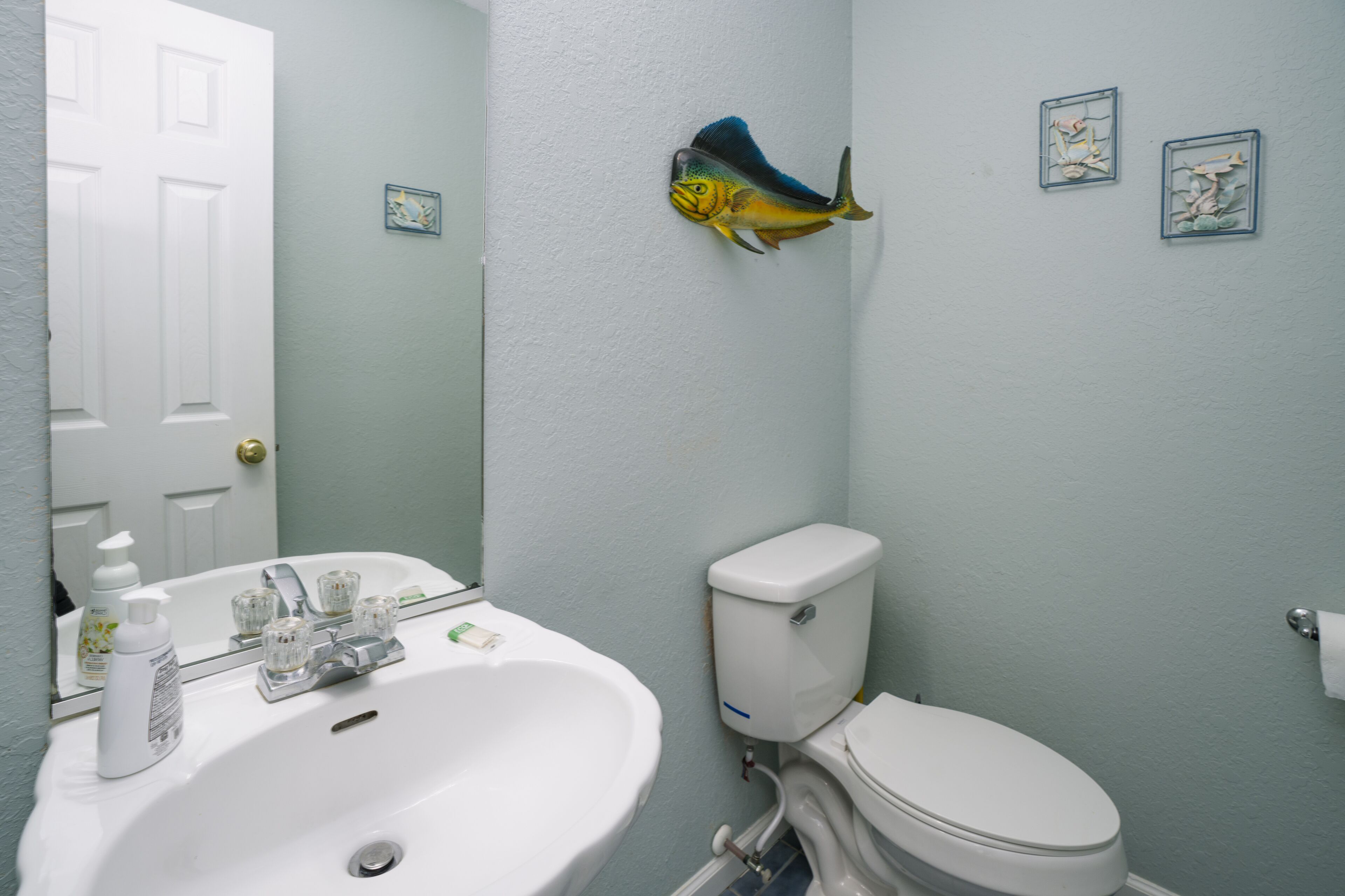 Een badkamer met een wit wastafel, toilet en een visdecoratie aan de muur.