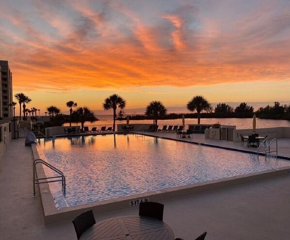 Relax by the oceanfront pool, surrounded by lounge chairs and umbrellas.