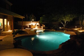 A swimming pool with a stone edge, a hot tub, and a covered seating area at night. -  Executive Relaxed Living Home 5BR/3B Pool & Spa in Estrella Mt Ranch (Goodyear)