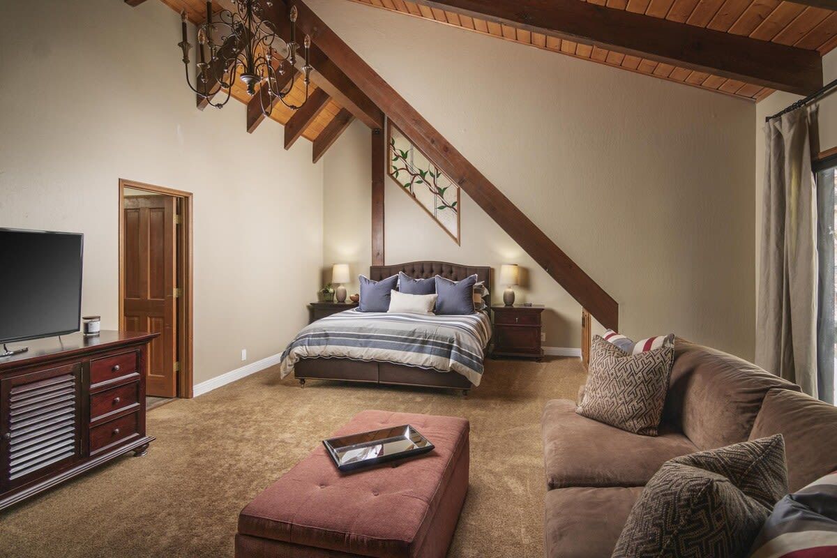 Une chambre à coucher comprenant un lit, une télévision, une commode, un canapé et un lustre.