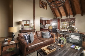 A spacious living room with a leather sofa, a coffee table, and a dining area with chairs and a chandelier.