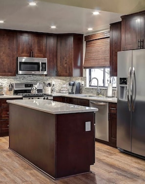 A modern kitchen with dark wood cabinets, stainless steel appliances, and a central island.