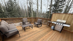 A wooden deck with outdoor furniture, a grill, and a propane tank.