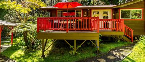 A wooden house with a red balcony and a red umbrella.