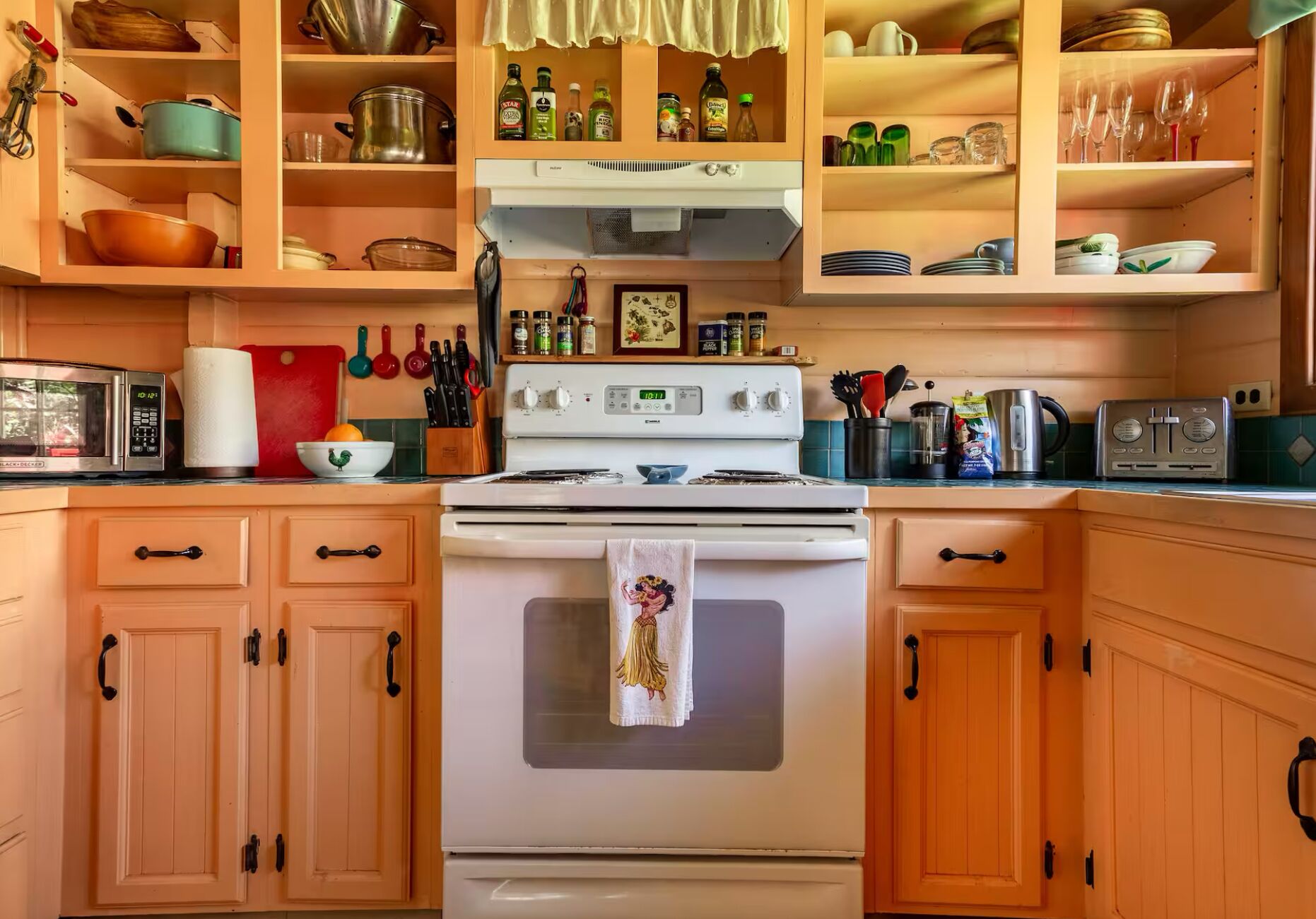 A kitchen with wooden cabinets, a stove, a microwave, and various kitchen utensils and appliances.