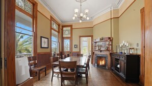 A dining area with a large wooden table and chairs, a fireplace, and a view of the outdoors.