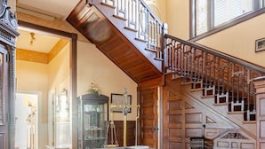 A grand staircase with a wooden finish and a glass railing, leading to an upper floor.