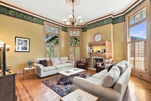 A spacious living room with a fireplace, comfortable seating, and large windows with decorative glass.