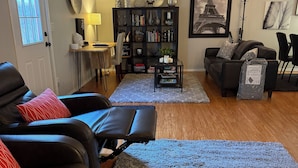 Un salon avec un canapé en cuir noir, une table basse et une bibliothèque.