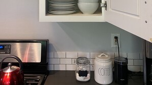 Une cuisine avec un meuble blanc contenant des assiettes, des bols et des vases décoratifs.