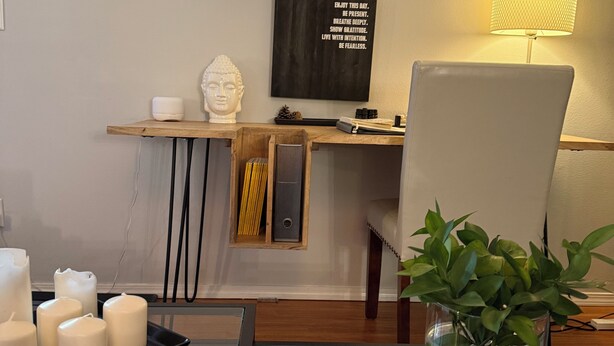 Un salon moderne avec une table basse en verre, une statue de Bouddha, une citation inspirante sur le mur et une lampe.