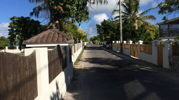 Une rue résidentielle avec une maison blanche, une clôture en bois et un ciel dégagé.