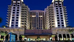 Un hotel de varios pisos con un atrio central, balcones en cada planta y un cartel que indica una zona de ventas.