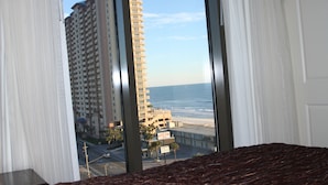 Habitación de hotel con un ventanal que ofrece vistas a un edificio alto y a la playa.