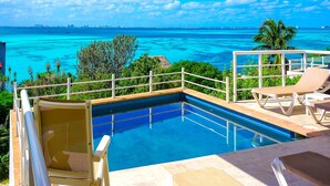 Une piscine avec vue sur l’océan et, en arrière-plan, le panorama de la ville.