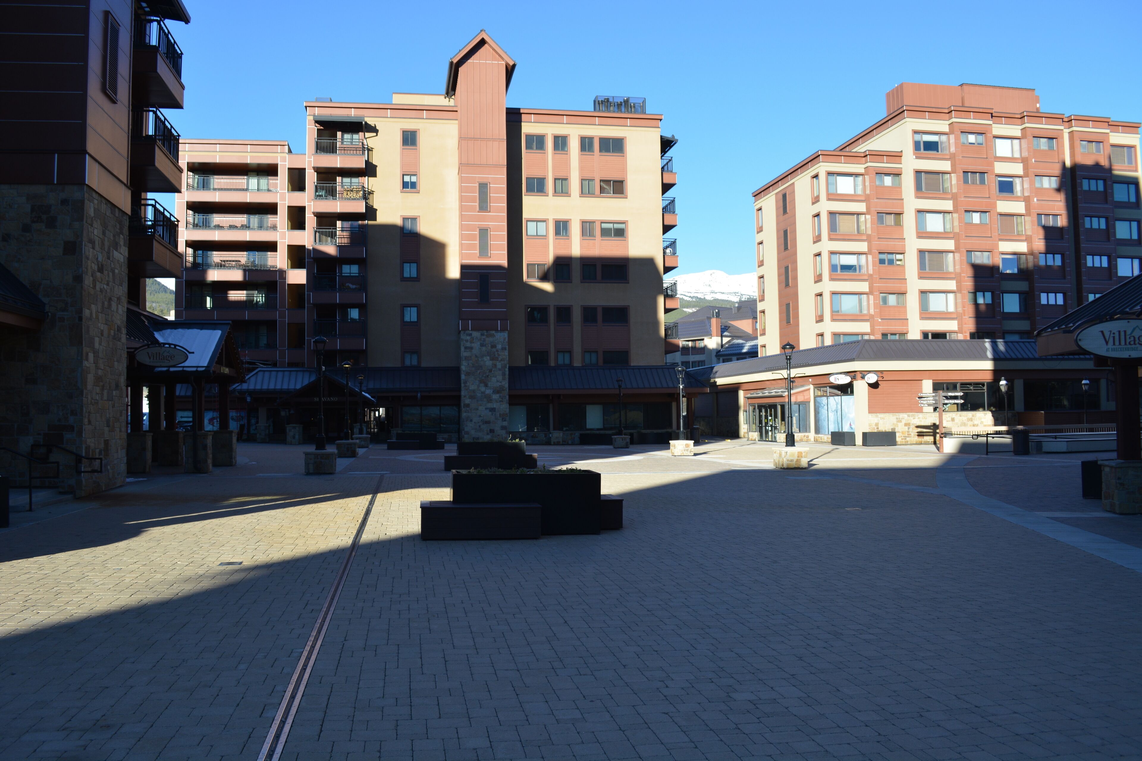 A hotel courtyard with a central stone monument, multiple-story buildings with balconies, and a clear blue sky.