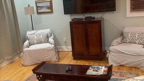 Una sala de estar con sofá, mesa de centro, televisor y aparador.