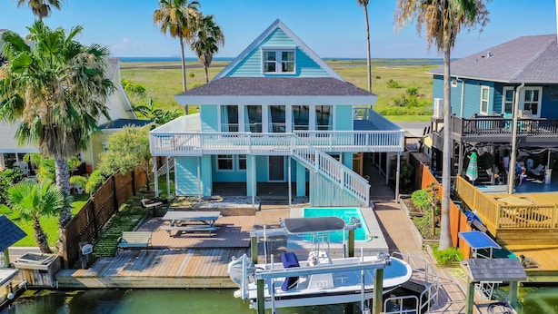 A waterfront house with a dock, a boat, and a pool.