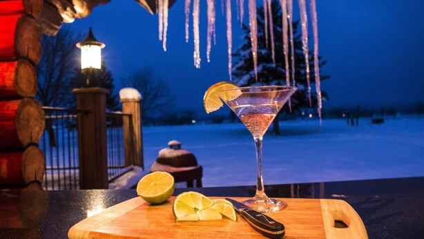 Martini-lasi, jossa on sitruunaviipale, puisella leikkuulaudalla, ja vieressä veitsi sekä kokonainen sitruuna.