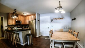 Una cocina moderna con armarios de madera, electrodomésticos de acero inoxidable y una zona de bar.