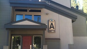 Un edificio con puerta roja, ventanas grandes y un cartel que indica 'Unidades 1-20'.