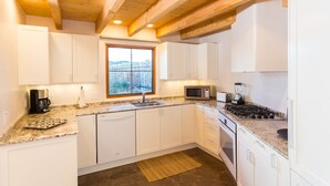 Eine moderne Küche mit weißen Schränken, Granit-Arbeitsplatten, einem eingebauten Backofen und einem Fenster mit Blick.